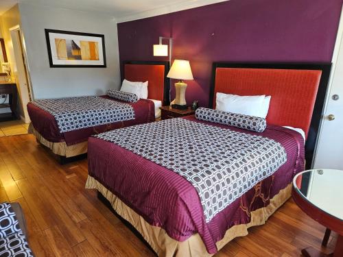 two beds in a hotel room with purple walls at Fullerton Inn in Fullerton