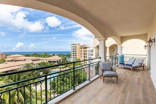 a balcony with two chairs and a view of the ocean at Designers Delight 3 BR w Pool Gym Tennis Courts in Cupecoy