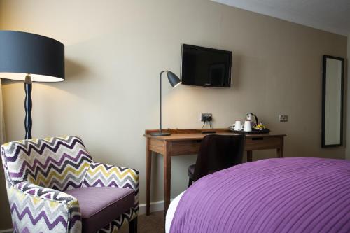 a hotel room with a purple bed and a desk at Toby Carvery Exeter M5 J30 by Innkeeper's Collection in Exeter
