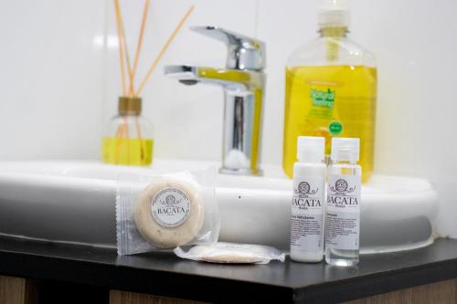 a bathroom sink with two bottles of soap and a sponge at Hotel Bacata Plaza in Zipaquirá