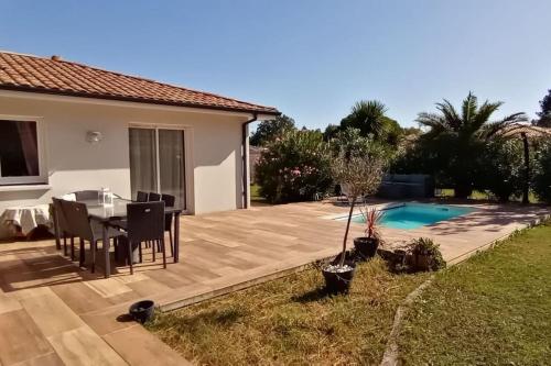 un patio avec une table et une piscine dans l'établissement Villa Océan, environnement calme avec piscine chauffée 10 min de l'océan, à Le Porge