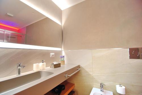 un bagno con lavandino e specchio di BURNÌA Sicily Holiday House a Palermo