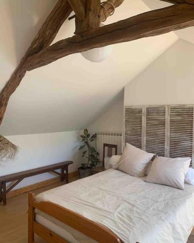 une chambre avec un lit blanc dans un grenier dans l'établissement La petite maison de Larroque, à Cassagnes