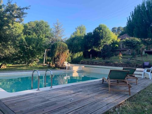 une terrasse en bois avec une chaise près de la piscine dans l'établissement La petite maison de Larroque, à Cassagnes