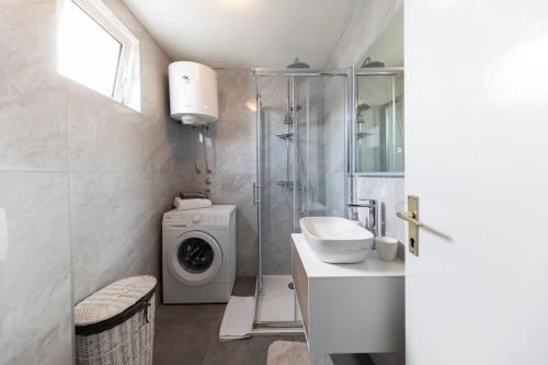 a bathroom with a shower sink and a washing machine at Puntamika studio in Zadar