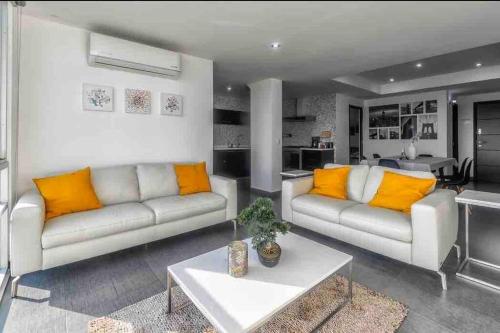 a living room with two couches and a table at Luxury Chapultepec Apartment in Guadalajara