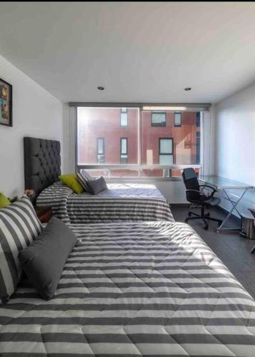 a bedroom with two beds and a large window at Luxury Chapultepec Apartment in Guadalajara