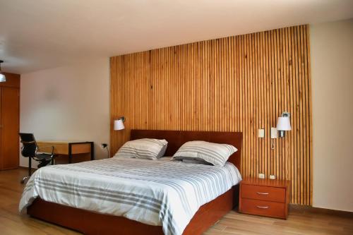 a bedroom with a bed and a wooden wall at CASAS FREDA - Centro Historico Departamentos in San Luis Potosí