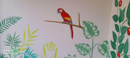 a red bird sitting on a branch with plants at Le GANGA LODGE in Ndangane