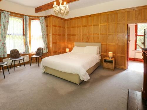 1 dormitorio con cama, sillas y lámpara de araña en Highwood Lodge, en Huddersfield
