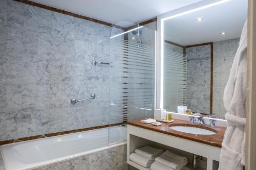 a bathroom with a tub and a sink and a shower at Royal Garden Champs-Élysées in Paris