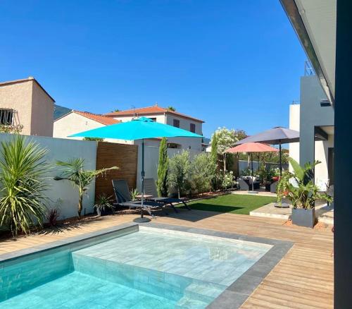- une piscine avec un parasol à côté d'une maison dans l'établissement Magnifique villa avec piscine, à Sorède