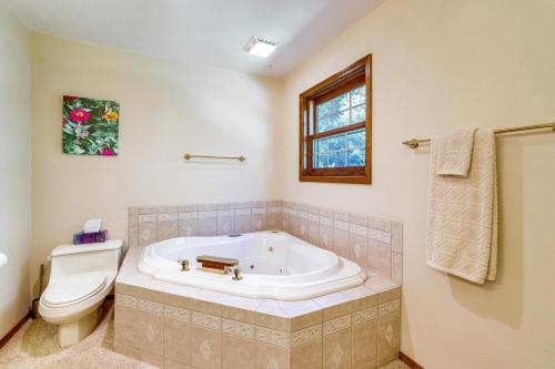 a bathroom with a tub and a toilet and a window at Just a Cast Away Cassville Cabin with Covered Deck in Cassville