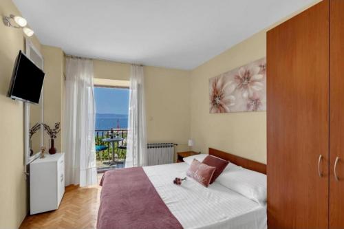 a bedroom with a bed and a television and a balcony at Apartments and rooms by the sea Podgora, Makarska - 2623 in Podgora