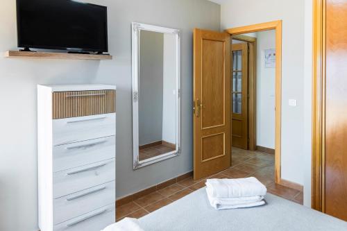 una camera con letto, TV e specchio di Mirador da Ria resort nautico Portosin a Goyanes