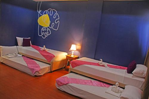 two beds in a room with a blue wall at Hotel Palacio Puerto Princesa in Puerto Princesa City