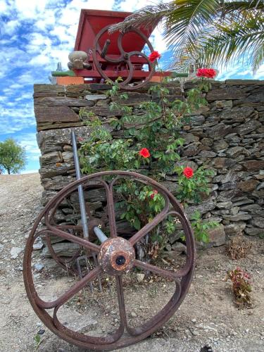 a large rusty wheel sitting next to a stone wall at Andar Moradia T2 na Casa Do Olival in São João da Pesqueira