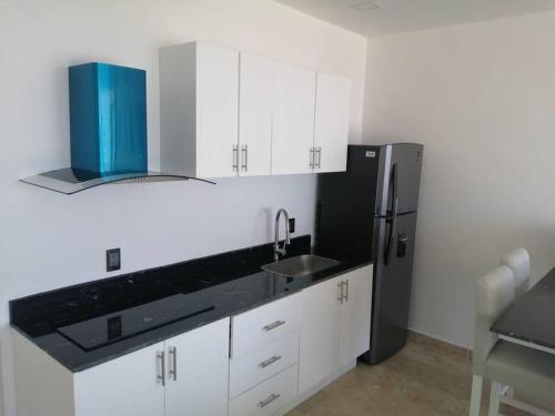 a kitchen with white cabinets and a black refrigerator at Mahaguay - Dpto 2 recamaras frente al mar in Mahahual