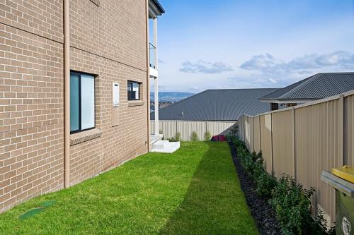 a yard next to a brick building with a fence at Hillgrove - Sophisticated & Refined Entertainer in Bathurst