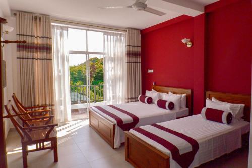 2 letti in una camera con pareti rosse e finestra di Villa Baywatch, Rumassala a Unawatuna