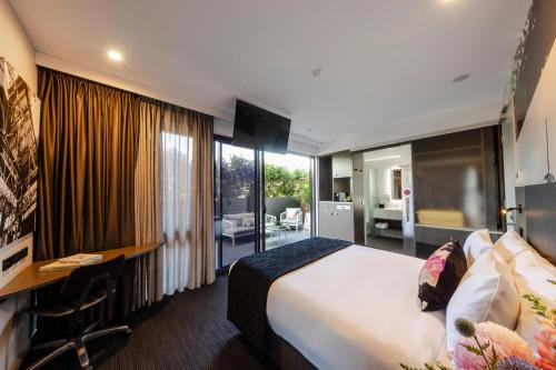 a hotel room with a large bed and a desk at Sage Hotel James Street in Brisbane