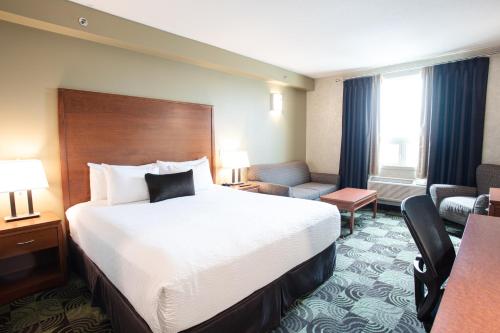a hotel room with a large bed and a couch at Deerfoot Inn and Casino in Calgary