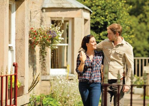 a man and a woman walking outside of a house at Parmontley Hall Lodges in Whitfield