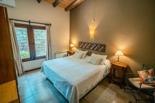 ein Schlafzimmer mit einem weißen Bett und einem Fenster in der Unterkunft Fabuloso descanso en Mendoza, Pileta, Zona Bodegas in Lunlunta