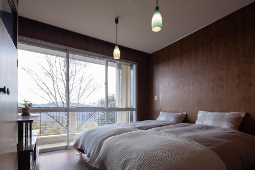 a bedroom with a large bed and a large window at Villa TEN ZAN - 岐阜 ヴィラ テンザン - in Mizunami