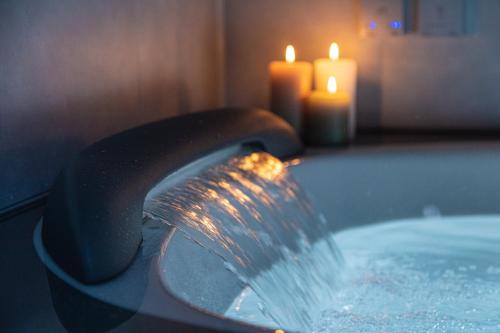 a faucet pouring water into a tub with two candles at Villa TEN ZAN - 岐阜 ヴィラ テンザン - in Mizunami