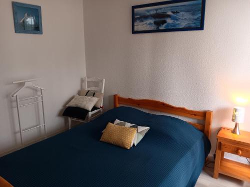 - une chambre avec un lit bleu et une chaise dans l'établissement Bel Appartement Moderne à Capbreton avec Wifi et Parking Privé - FR-1-239-803, à Capbreton