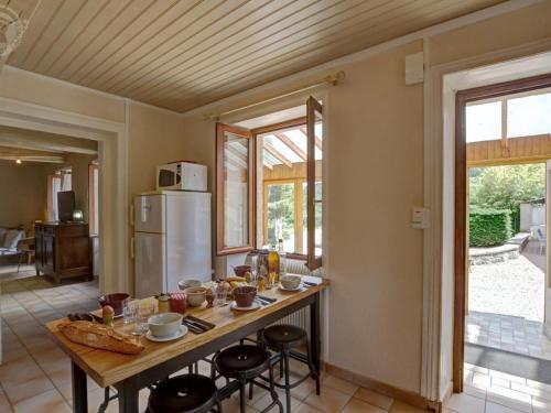 a kitchen with a table with chairs and a refrigerator at Gîte avec piscine, cheminée, jardin, et animaux acceptés - FR-1-496-32 in Belmont-de-la-Loire