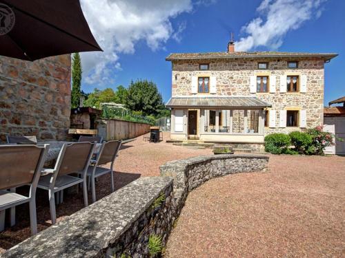 a building with chairs and an umbrella in front of it at Gîte avec piscine, cheminée, jardin, et animaux acceptés - FR-1-496-32 in Belmont-de-la-Loire