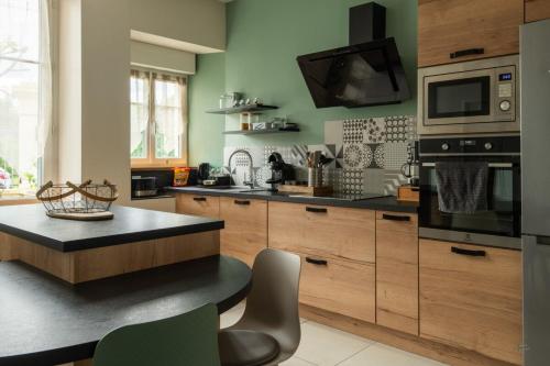 une cuisine avec des armoires en bois et un comptoir noir dans l'établissement Maison en bord de Creuse - 2min d'Argenton, à Le Pêchereau