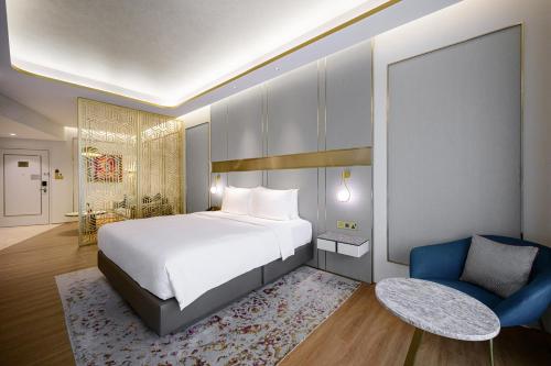 a bedroom with a large bed and a blue chair at Resorts World Sentosa - Crockfords Tower in Singapore