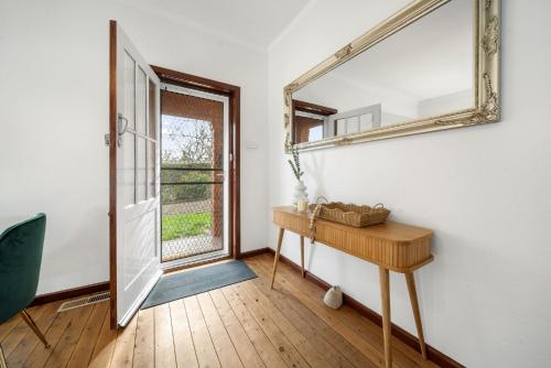 a mirror on a wall in a room with a table at 3-Bed Family Haven with Garden & BBQ Area in Canberra