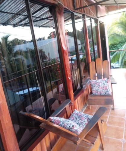 two chairs sitting on a porch with windows at Surá House Corcovado SuriNico Room With AC in Puerto Jiménez
