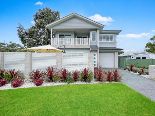 a house with a fence and a grass yard at Coastline Cove - Modern Townhome Oasis in Shellharbour