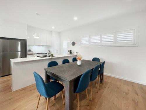 a kitchen and dining room with a table and blue chairs at Coastline Cove - Modern Townhome Oasis in Shellharbour