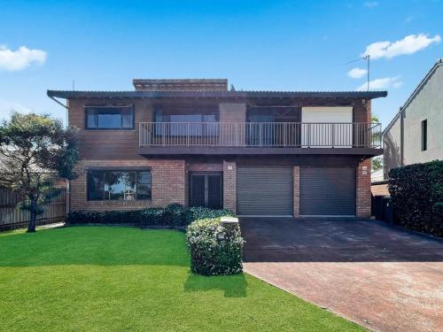 a brick house with a balcony and a yard at Family Getaway Opposite Warilla Beach in Lake Illawarra