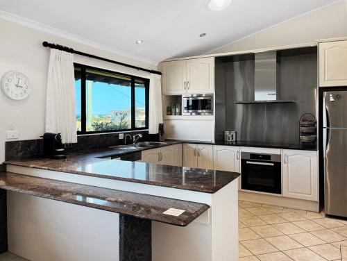 a kitchen with white cabinets and a large counter top at Family Getaway Opposite Warilla Beach in Lake Illawarra