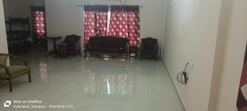 a room with chairs and a table and curtains at Sakez Homestays K in Hyderabad