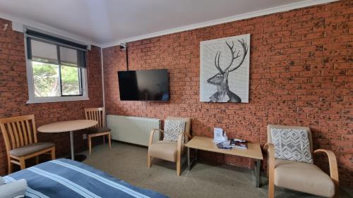 a bedroom with a brick wall with a table and chairs at Merrijig Motor Inn in Merrijig