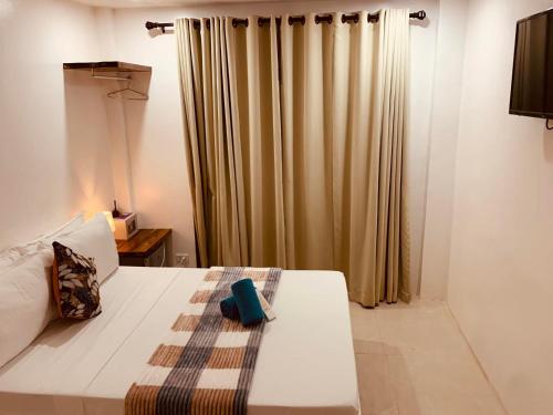 a bedroom with a white bed and a curtain at La Sirenne Inn in El Nido