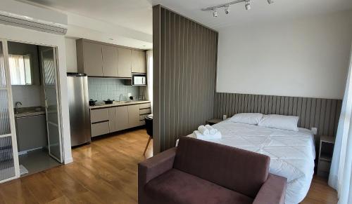a bedroom with a bed and a chair and a kitchen at Blend Coliving One - 2a in Ribeirão Preto
