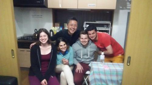a group of people posing for a picture in a kitchen at J's Backpackers in Tokyo