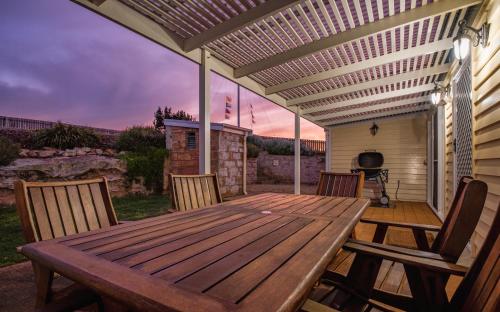 a wooden table and chairs on a deck with a pergola at Surfside Holiday Park Warrnambool in Warrnambool
