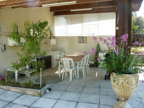 un patio avec une table, des chaises et des plantes dans l'établissement Maison St-Georges-d'Oléron avec piscine privée et véranda, 4 couchages, proche plage - FR-1-246A-312, à Saint-Georges-dʼOléron