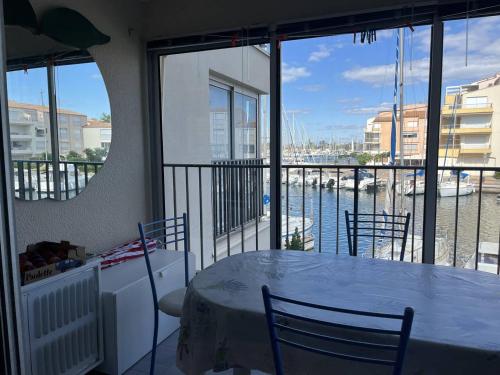- une table et des chaises dans une chambre avec vue sur l'eau dans l'établissement Appartement T2 au Cap d'Agde - 6 pers, Parking privé, Proche plage et commerces - FR-1-749-70, au Cap d'Agde
