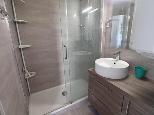 La salle de bains est pourvue d'une douche et d'un lavabo blanc. dans l'établissement Confortable T3 avec PK privé, climatisation et accès direct à la plage - FR-1-472-201, à Sète